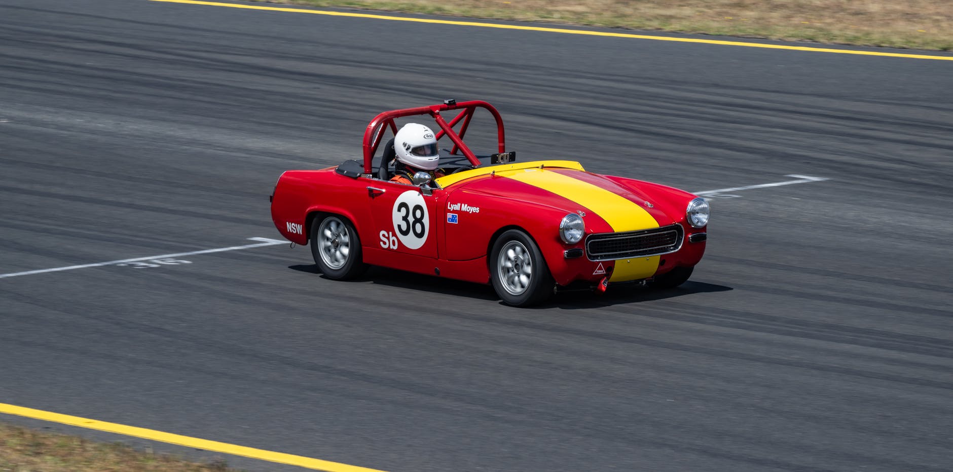 Czerwony klasyczny Aston Martin pędzący po torze wyścigowym