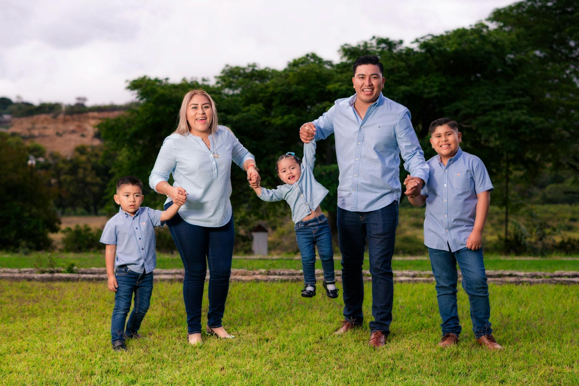 Rodzina z trójką dzieci w podobnych strojach bawi się na słońcu na dworze