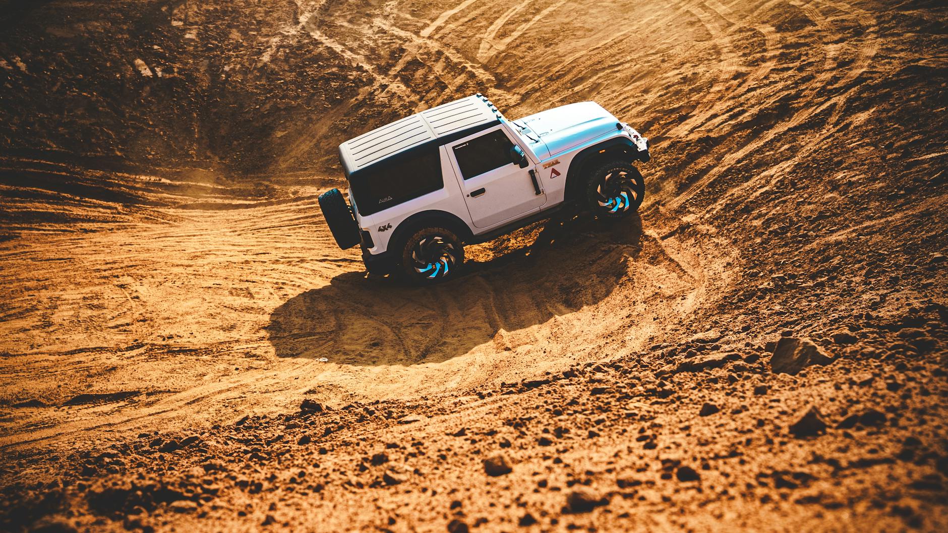 SUV jedzie dynamicznie po piaszczystych wydmach, pokaz off-roadu