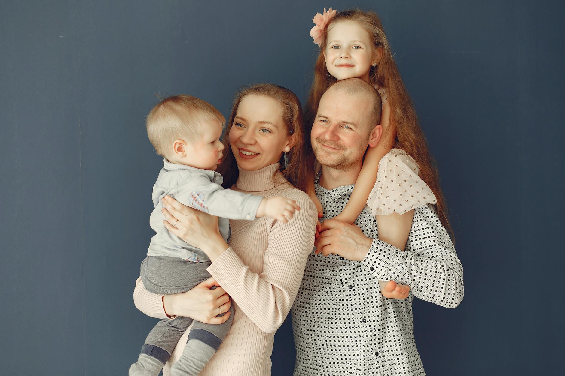 Uśmiechnięci rodzice z dwójką dzieci pozują razem w domu