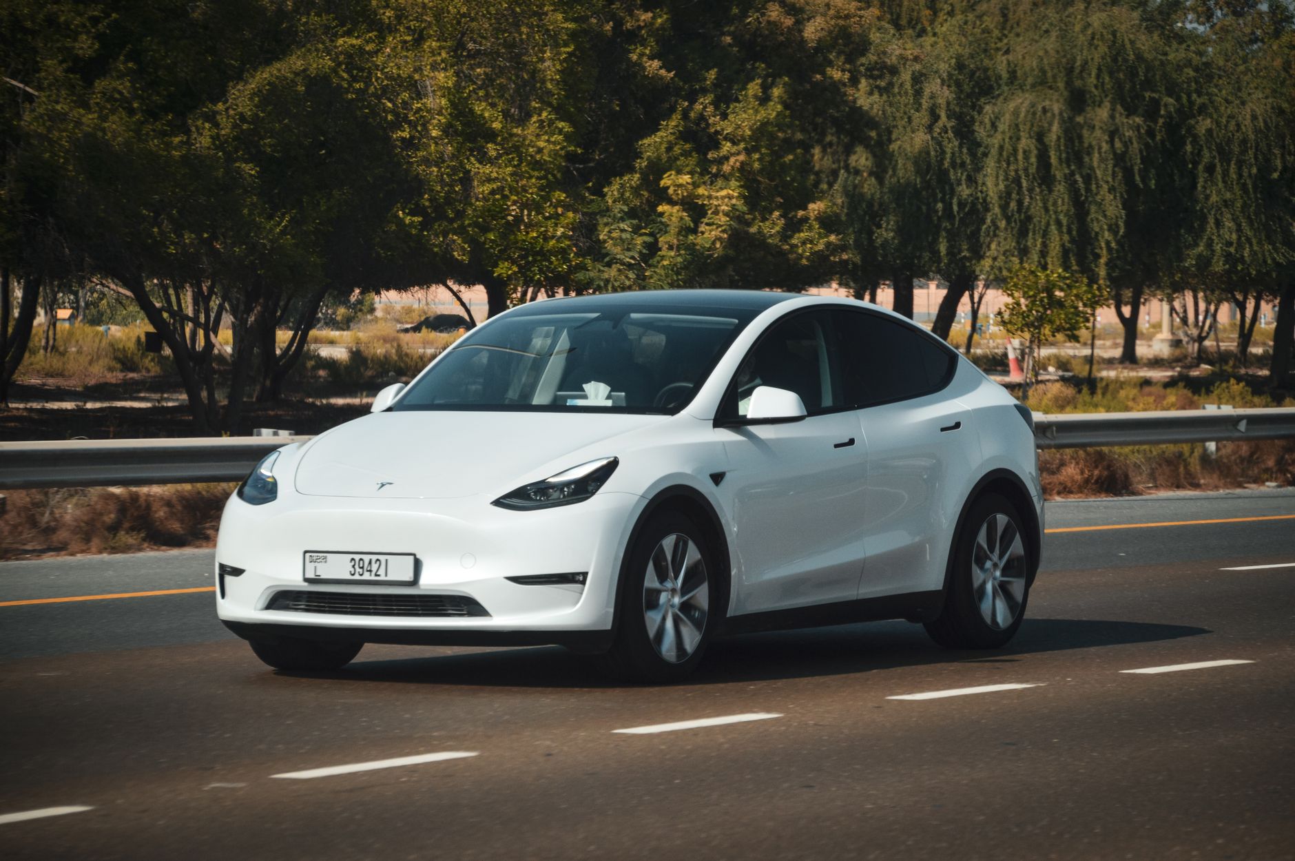 Biała Tesla jedzie słoneczną autostradą podczas zagranicznego roadtripu