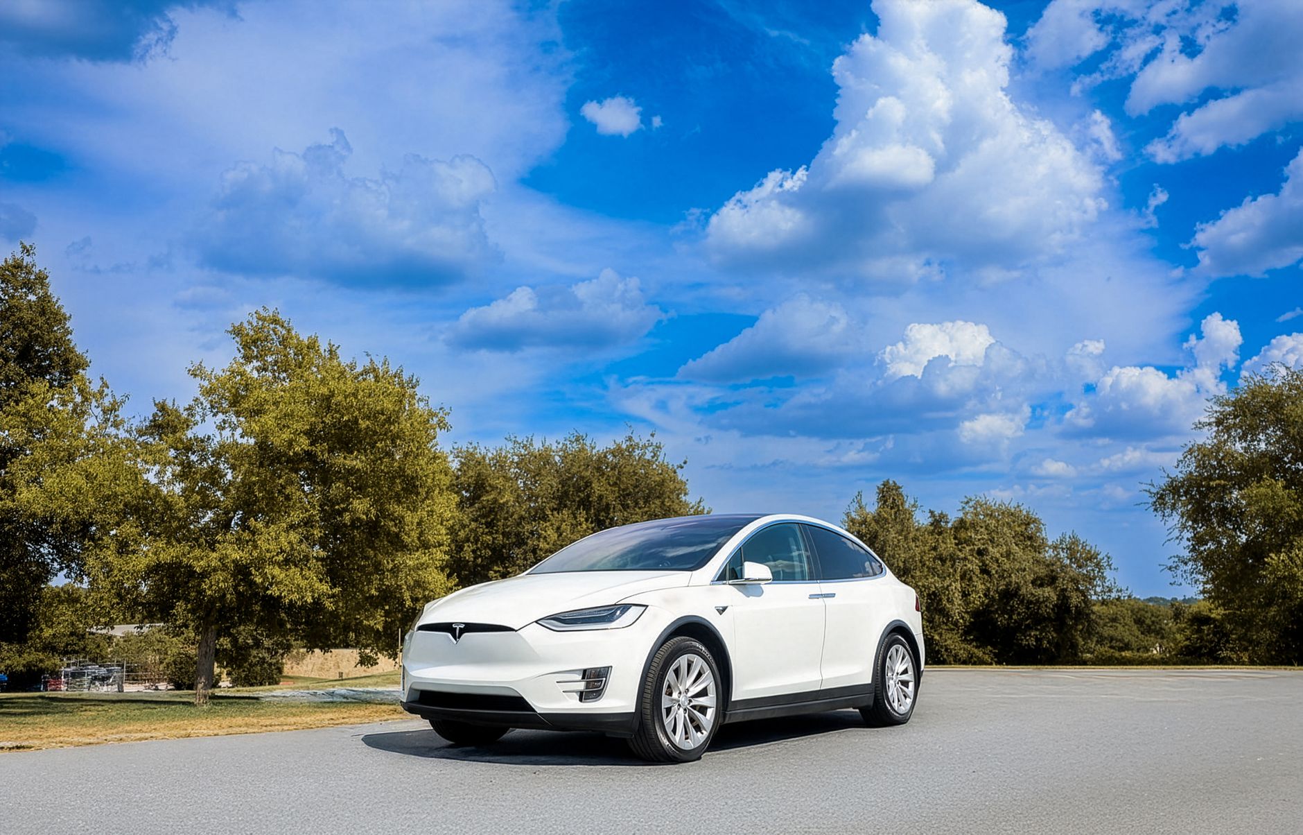 Biała Tesla na tle gór i nieba z chmurami podczas roadtripu po Europie