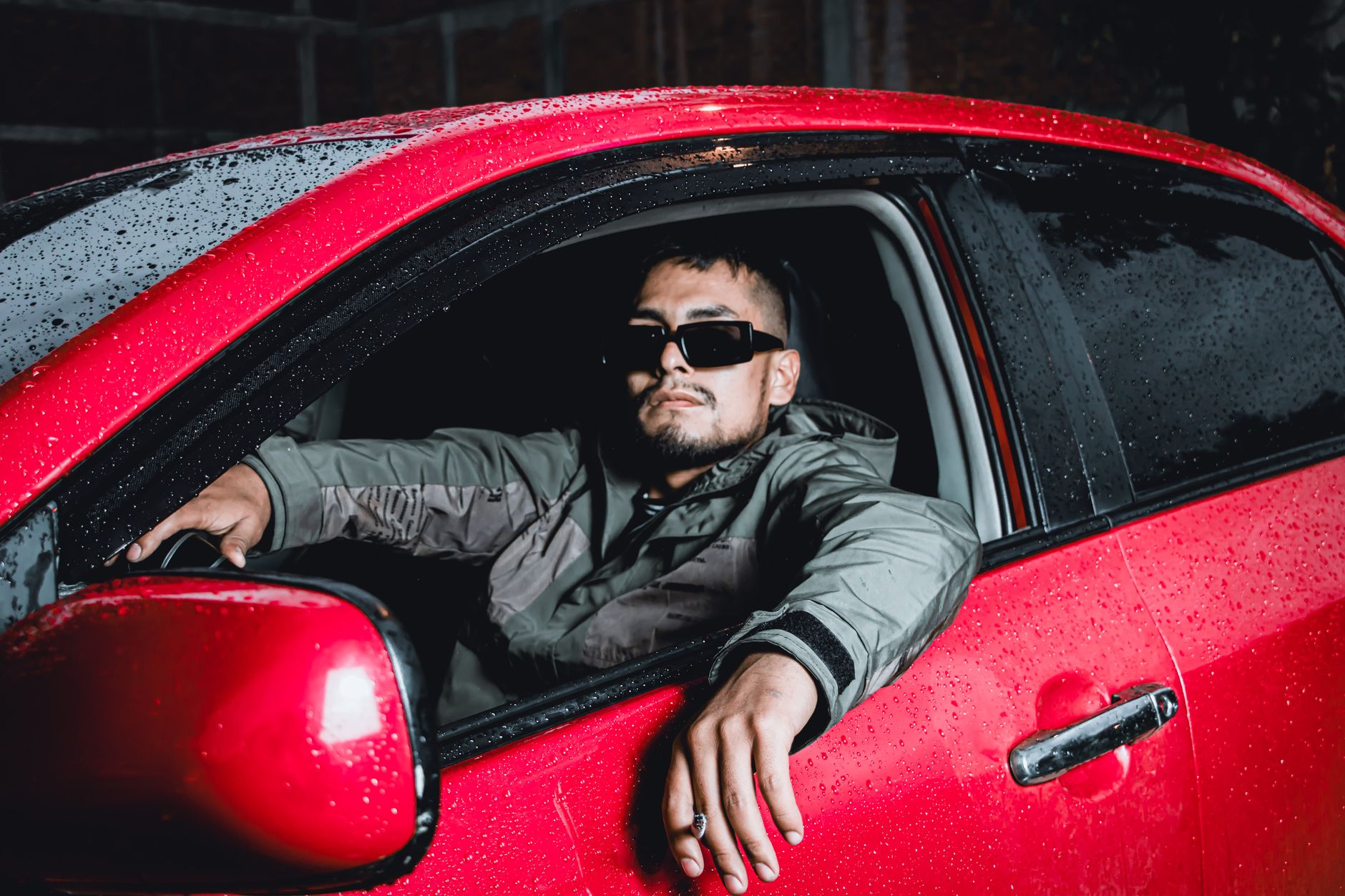 Młody kierowca w czerwonej Toyocie Aygo X nocą w deszczu