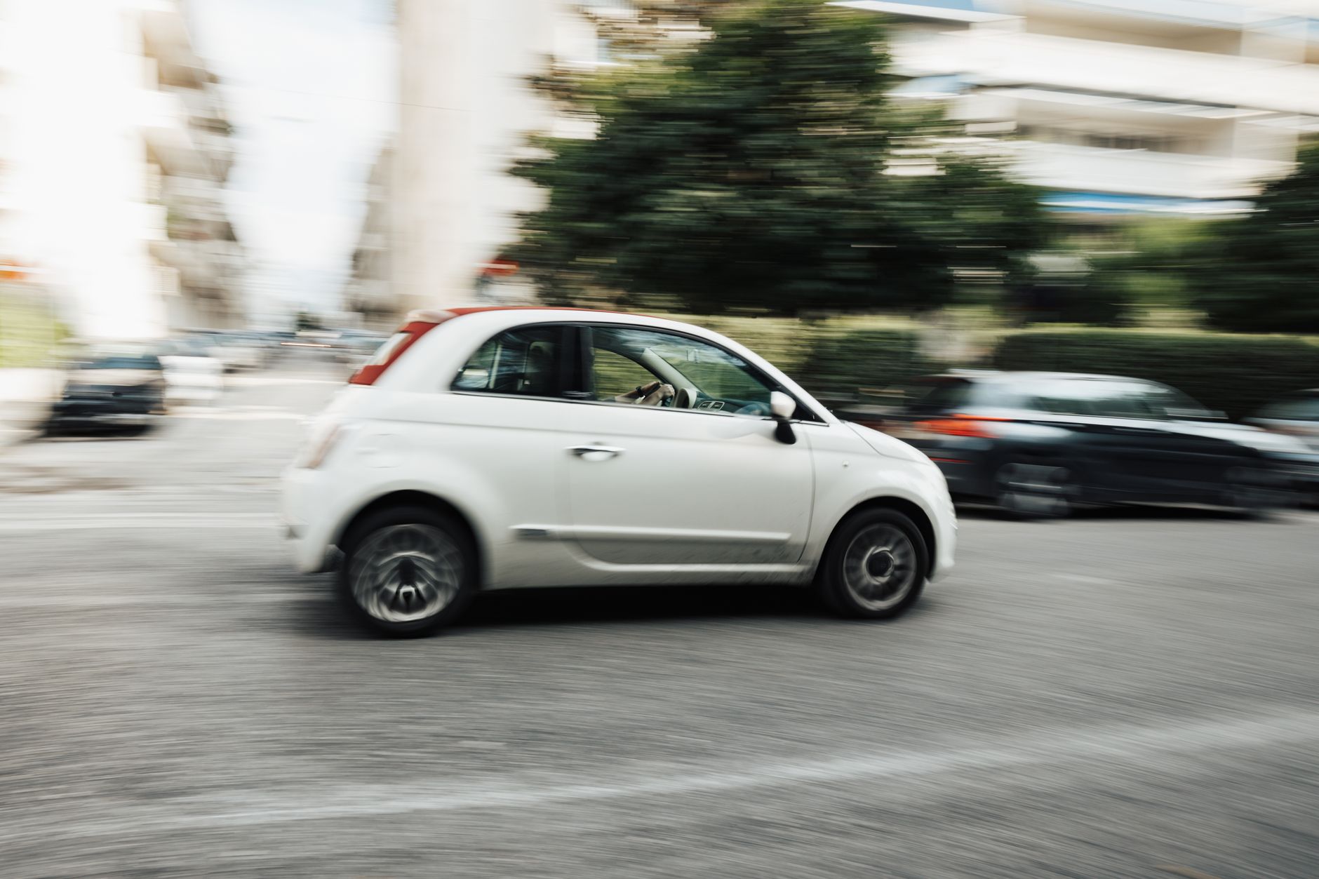 Biały Hyundai i10 jedzie szybko po miejskiej ulicy