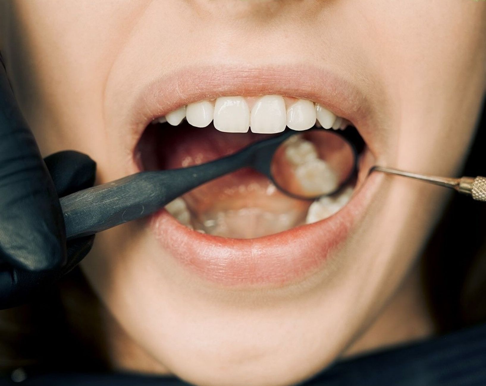 Dentysta bada dziąsła pacjenta nowoczesnym sprzętem podczas kontroli
