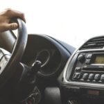Dlaczego Toyota nie chce odpalić mimo sprawnego kluczyka? Najczęstsze przyczyny Dłoń kierowcy na kierownicy Toyoty, widoczna deska rozdzielcza